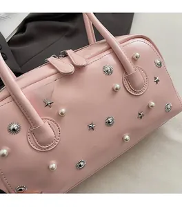 Detail of pink leather bag with white pearls, star rivets, and floral metal accents