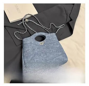 Détail du sac seau en jean bleu clair avec coutures matelassées et bandoulière chaîne