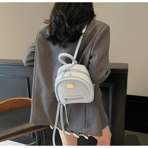Close-up of mint blue faux leather backpack with gold metal plate and zipper detail