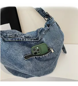 Detail of blue denim crossbody bag showing side zipper pocket and large storage capacity
