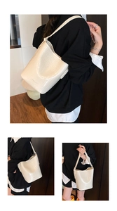 Detail of ivory crocodile pattern bucket bag showing wide shoulder strap and texture