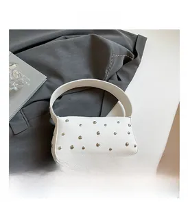 Detail showing white lychee grain leather texture and silver metal rivets on the handbag