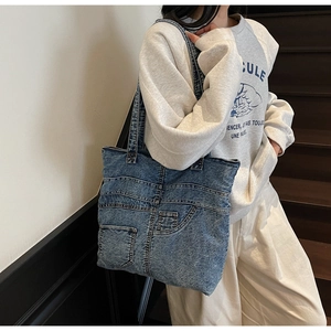 Detail of vintage patchwork denim tote bag with functional jeans pocket and retro wash