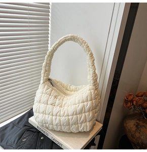 Close-up of beige quilted puffer bag featuring a textured lattice pattern and soft fabric