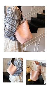Detail of pink crocodile embossed bucket bag with slim shoulder strap and top handle