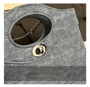 Gros plan d'un sac seau en denim montrant la texture matelassée et le fermoir argent