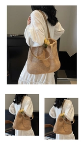 Detailed view of hollow woven texture and wide shoulder strap on khaki straw tote bag