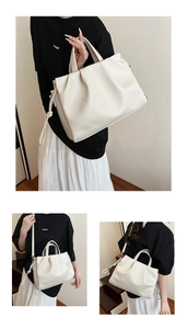 Detail of creamy white litchi pattern leather bag with ruched top and cylindrical handles