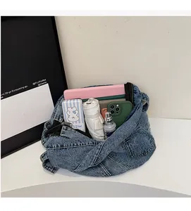 Top view of spacious interior of blue denim crossbody bag filled with daily essentials