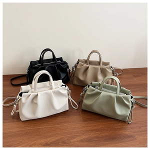 Detailed arrangement of pleated tote bags in black, beige, white and green on wood floor
