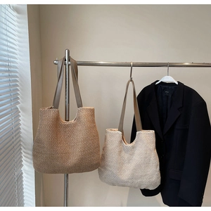 Detail of woven cotton straw tote bags in tan and cream with slim leather straps