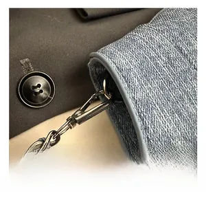 Détail du sac en jean bleu montrant le crochet en métal argenté et la bandoulière tressée