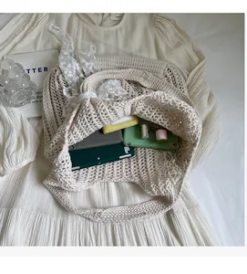 Macro view of beige knit tote bag with spacious interior and lace bow detail