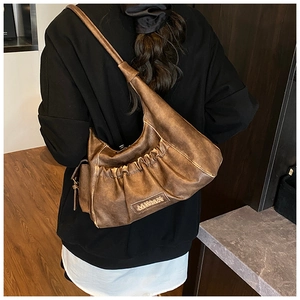 Close-up of vintage brown ruched underarm bag with MIKMIX logo and textured PU leather