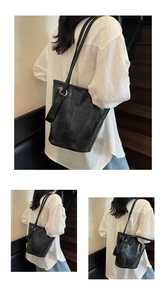 Detail of black crocodile texture tote bag with silver buckle on a wooden staircase