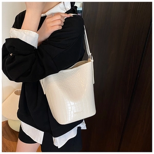 Detail of white crocodile pattern bucket bag with metal logo on a model