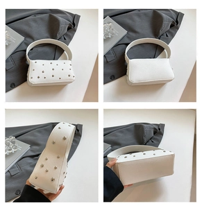 Detail view of white lychee leather handbag with silver rivets and integrated handle