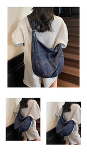Detail view of large denim crossbody bag showing contrast stitching and multiple pockets
