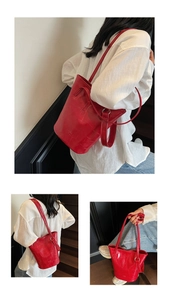 Detail view of a red crocodile embossed bucket bag with long strap and silver hardware