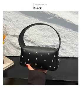 Detail of black pebbled leather handbag featuring silver studs and wide handle