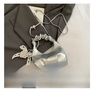 Détail du sac coquille argenté avec nœud en dentelle perlée et bandoulière chaîne