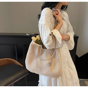 Close-up of beige woven tote bag with brown shoulder strap and floral interior details
