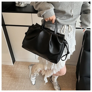 Detailansicht einer schwarzen Lederhandtasche mit Falten-Design und seitlichem Kordelzug