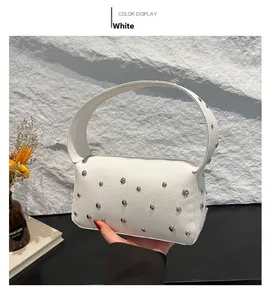 Detail of white lychee leather handbag with silver studs on rock texture background
