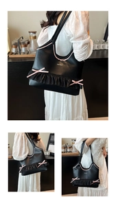 Detail of black tote bag featuring pink bow decoration and wavy ruffle trim accents