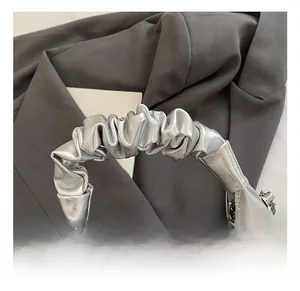 Détail du sac coquille argenté montrant la poignée plissée et les finitions métalliques