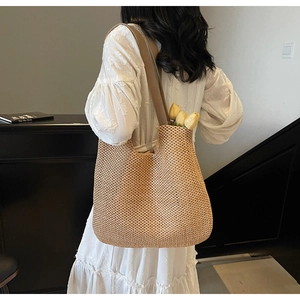 Detail of spacious woven straw tote bag with brown leather handles and yellow tulips