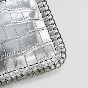 Detailed close-up of silver crocodile embossed leather and metallic woven chain border