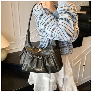 Detail of black pleated crescent hobo bag featuring silver MKMX metal logo and side pocket