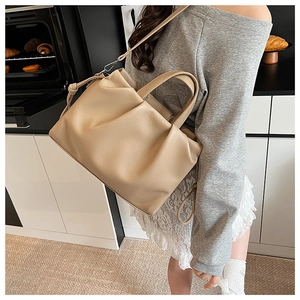 Borsa tote beige plissettata con trama litchi mostrata in un ambiente di pasticceria