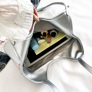 Spacious interior of silver handbag showing tablet, books and cosmetics storage space