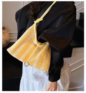 Détail du sac cabas en maille rayé jaune et blanc avec bandoulière nouée et anneau