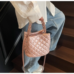 Detail of pink quilted rhinestone bucket bag with shiny metallic handle and chain strap