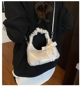 Détail du sac coquille blanc avec nœud en dentelle et pendentif en perles