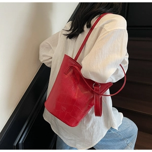 Close-up of red crocodile pattern bucket bag with adjustable strap worn by a model