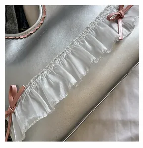 Macro detail of silver tote bag with pink leather bow and white translucent ruffled edges