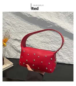 Close-up of red lychee grain leather handbag featuring silver punk stud decorations