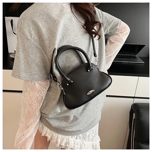 Detail view of black lychee grain shell bag with silver hardware and crossbody strap