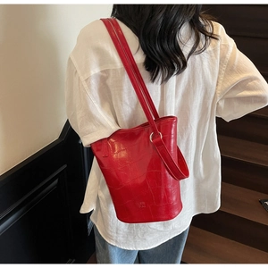 Macro detail of red oil wax bucket bag with crocodile embossed texture and long straps