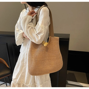 Straw tote bag detail showing large capacity and natural woven texture on a shoulder bag