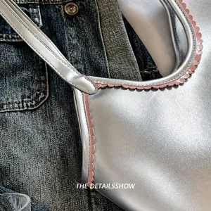 Detail of silver metallic leather handbag featuring pink scalloped edge trim over denim