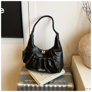 Close-up of black pleated faux leather bag with MKMX metal logo on silver luggage