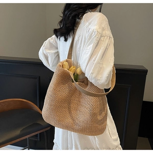 Detail of beige woven straw tote bag with wide strap and tulip flowers inside
