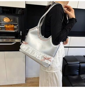 Silver tote bag with white lace ruffles and pink bows shown on a model's shoulder