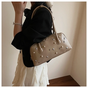 Detail of khaki shoulder bag featuring pearl studs and silver star metal ornaments