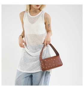 Detail shot of brown leather baguette bag featuring silver studs and wide strap